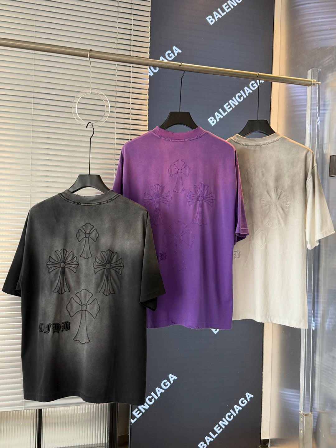 Short-sleeve T-shirts on hangers: black, purple, and cream with embroidered floral designs.