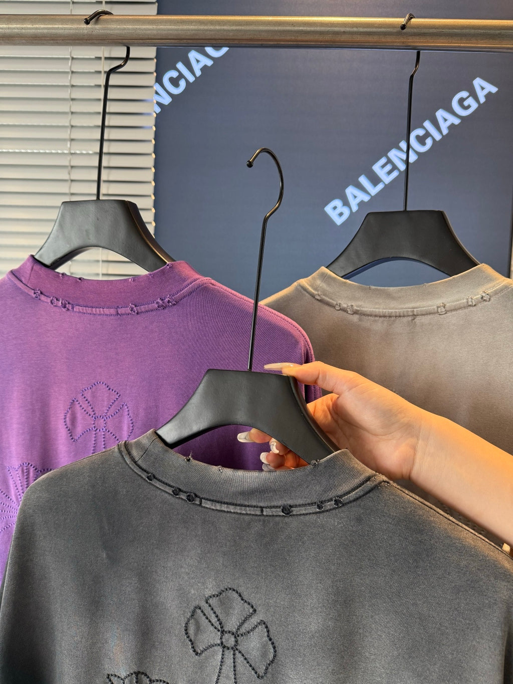 Short-sleeve T-shirts on hangers; gray front shows embroidered flower on the chest.