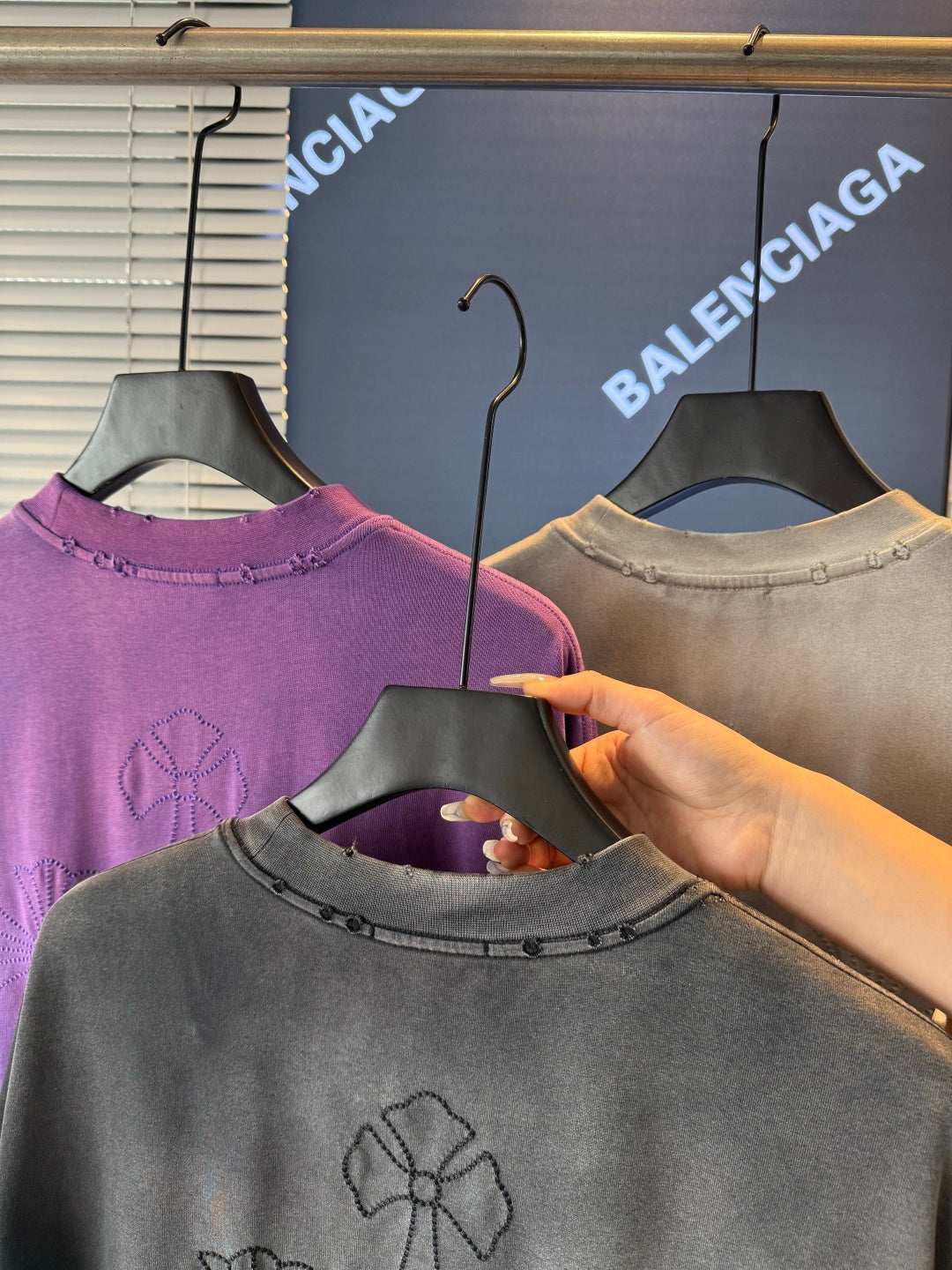 Short-sleeve T-shirts on hangers; gray front shows embroidered flower on the chest.