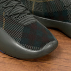 Burberry sneaker side close-up, dark plaid knit with grey rubber sole edge