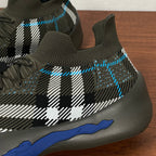 Burberry knit sneaker side close-up, black-and-white plaid with blue accents