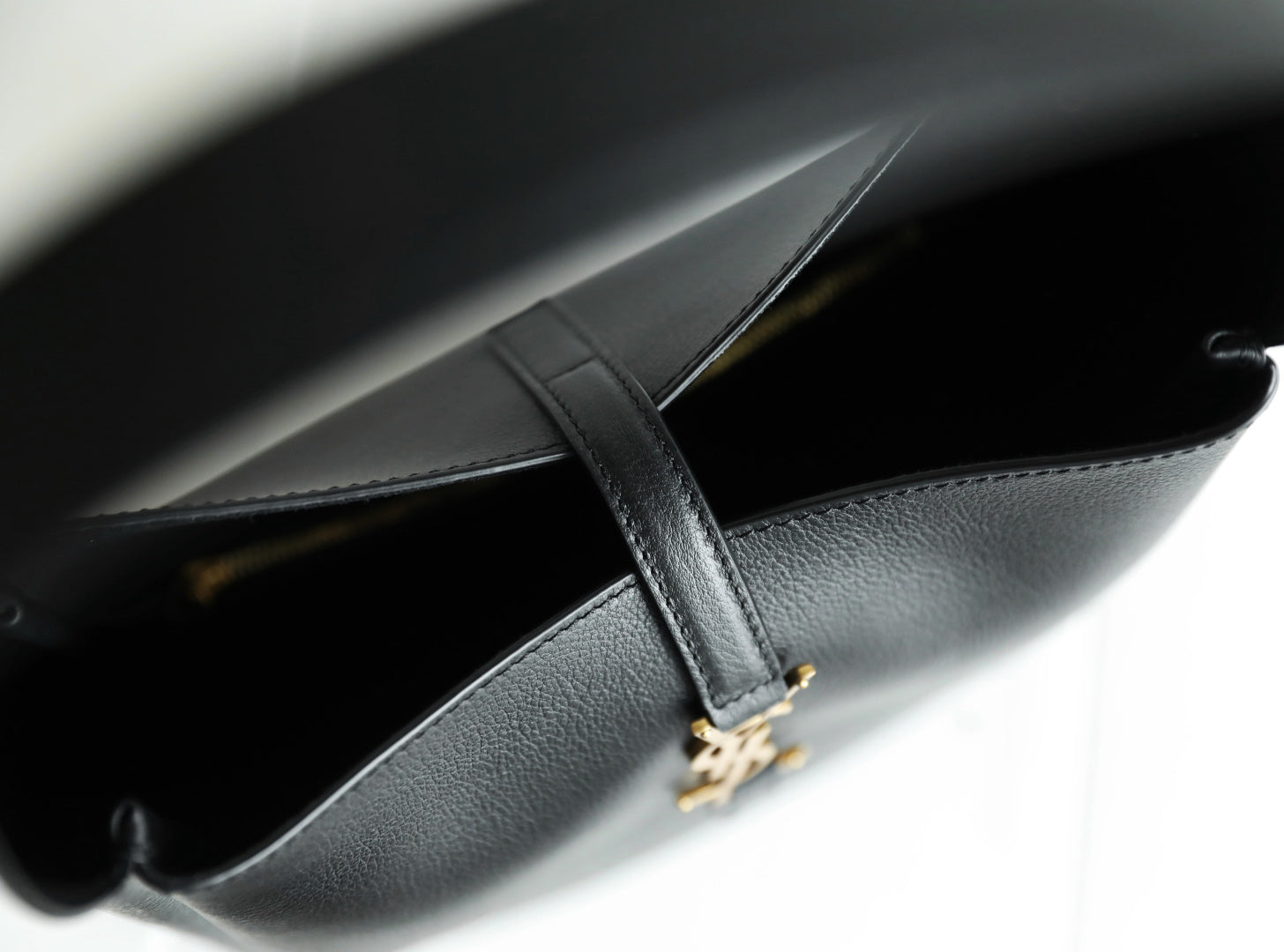Black YSL bag interior view with stitched edge and gold YSL charm