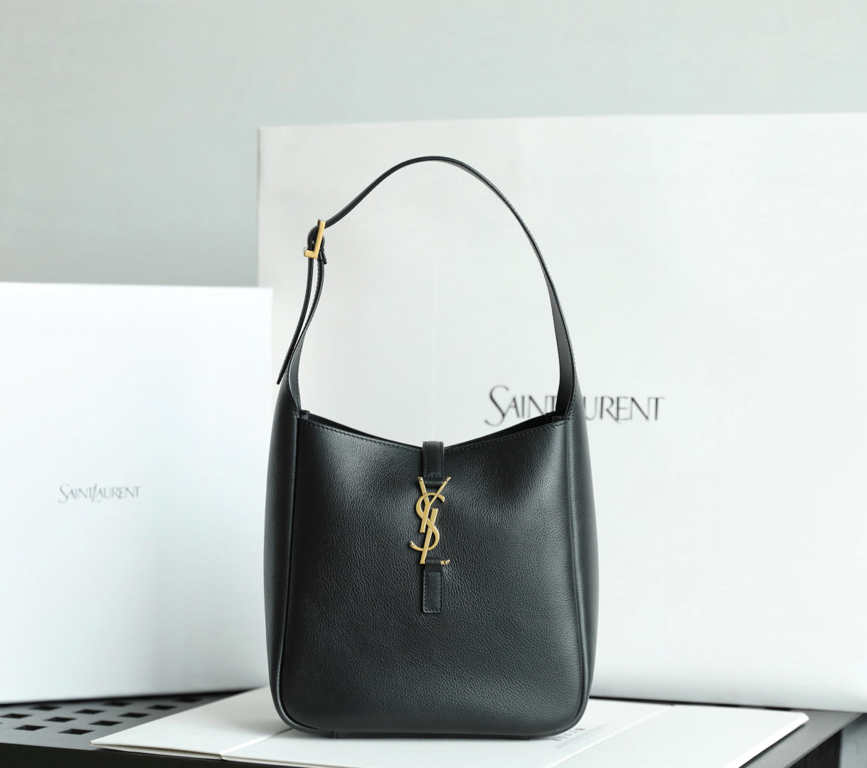Black YSL shoulder bag with gold YSL logo charm and structured curved top