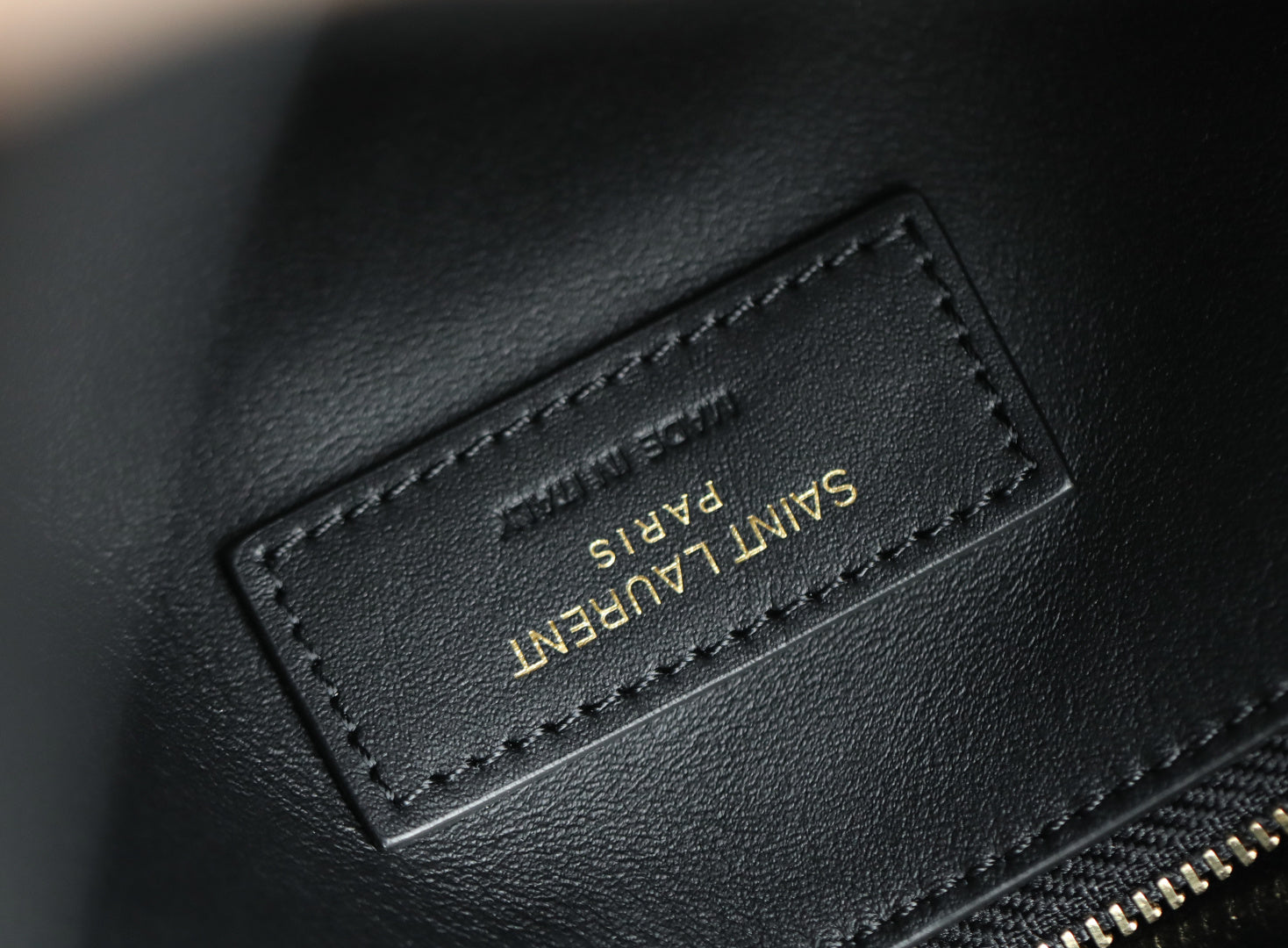 Black leather YSL bag tag with “SAINT LAURENT” text and stitching