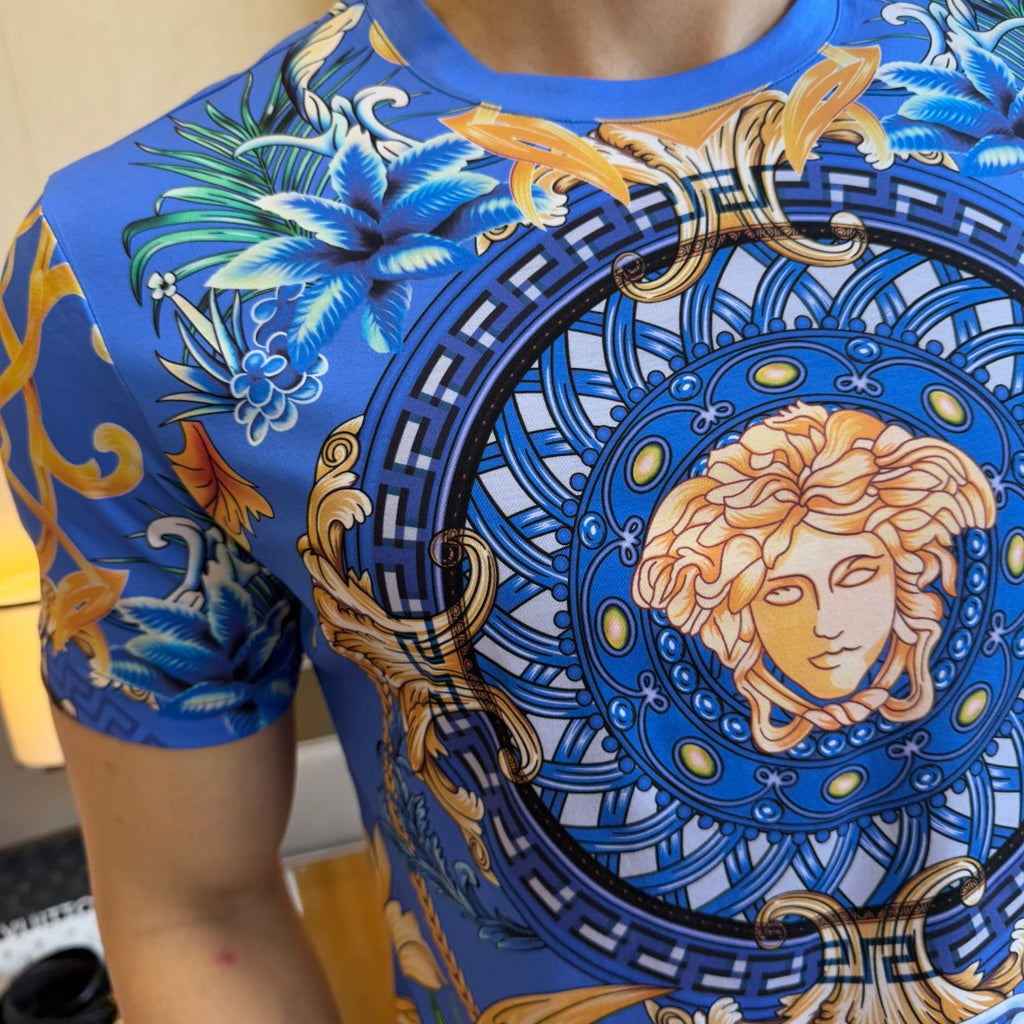 Blue graphic T-shirt close-up: circular Medusa portrait with swirl and floral motifs