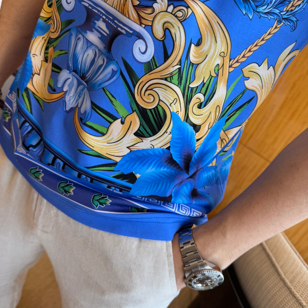 Blue graphic T-shirt hem detail with scrollwork print and small floral accents