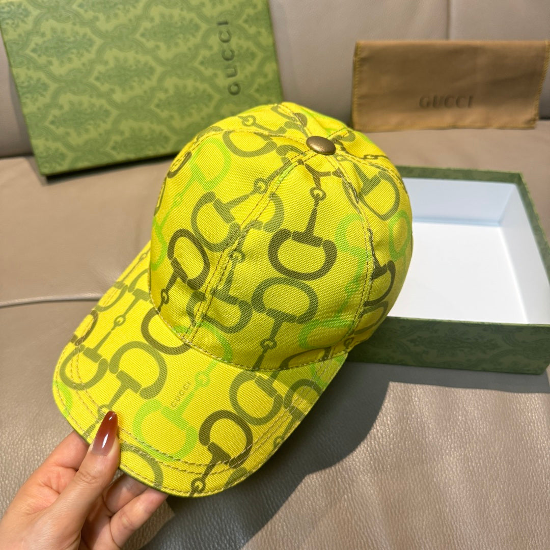 Yellow GG-print cap held in hand, curved brim and back panel.