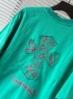 Turquoise short-sleeve T-shirt with large pink embroidered crest graphic on front