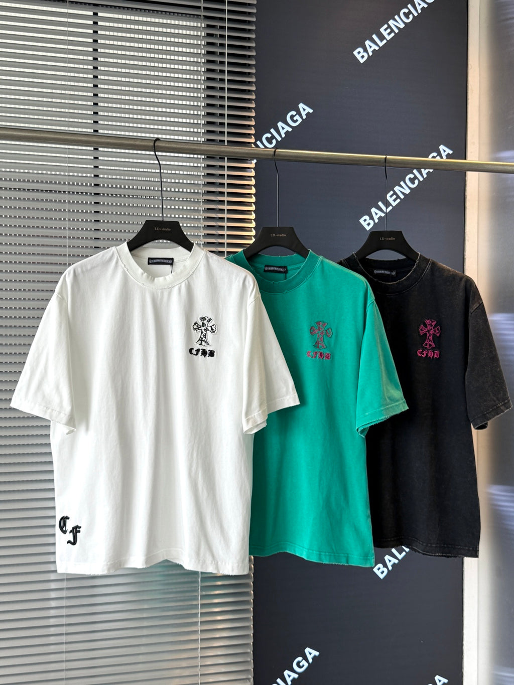 White short-sleeve T-shirt with black embroidered crest graphic on the chest