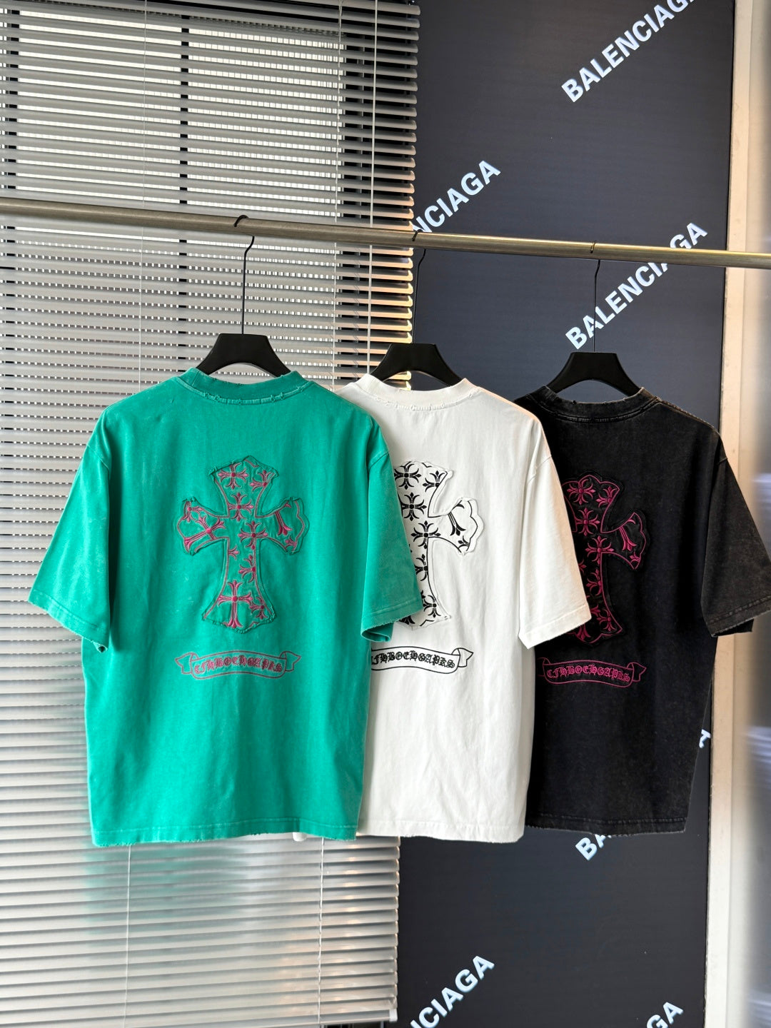 Turquoise, white, and black short-sleeve T-shirts with colorful embroidered crest graphics