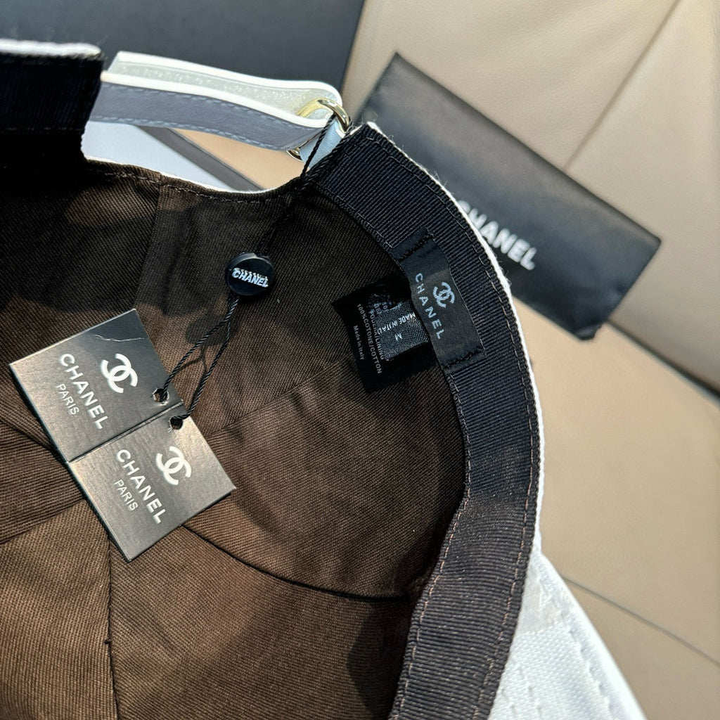 Chanel cap with dark fabric panels, adjustable strap, and hanging Chanel tags