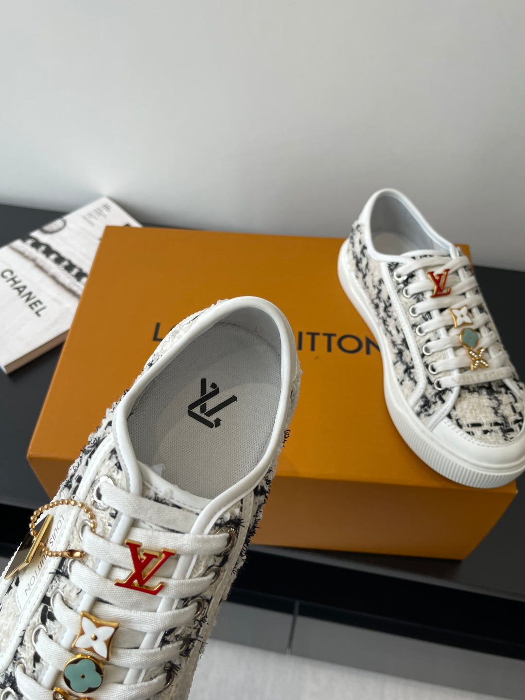 Louis Vuitton women's sneakers, white laces and black patterned upper with gold trim.
