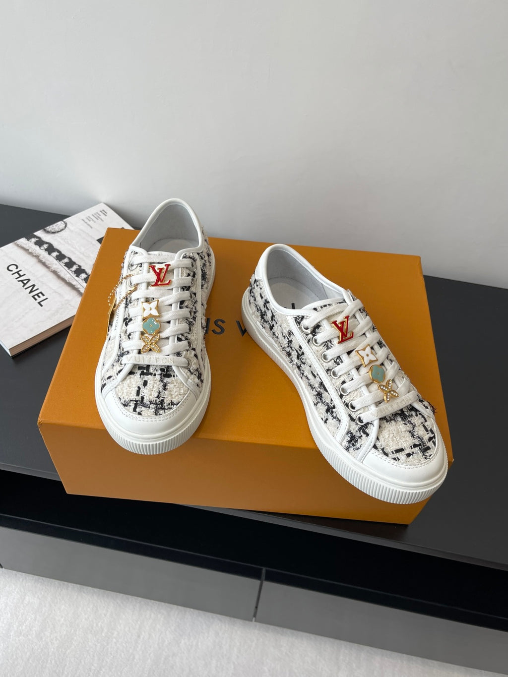 Louis Vuitton women's sneakers pair, white with black patterned uppers and lace-up front.
