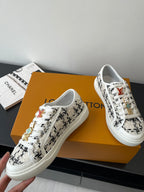 Louis Vuitton women's sneakers with white uppers and black patterned side panels, lace-up.