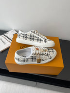 Louis Vuitton women's sneakers, white and black patterned upper with gold trim details.