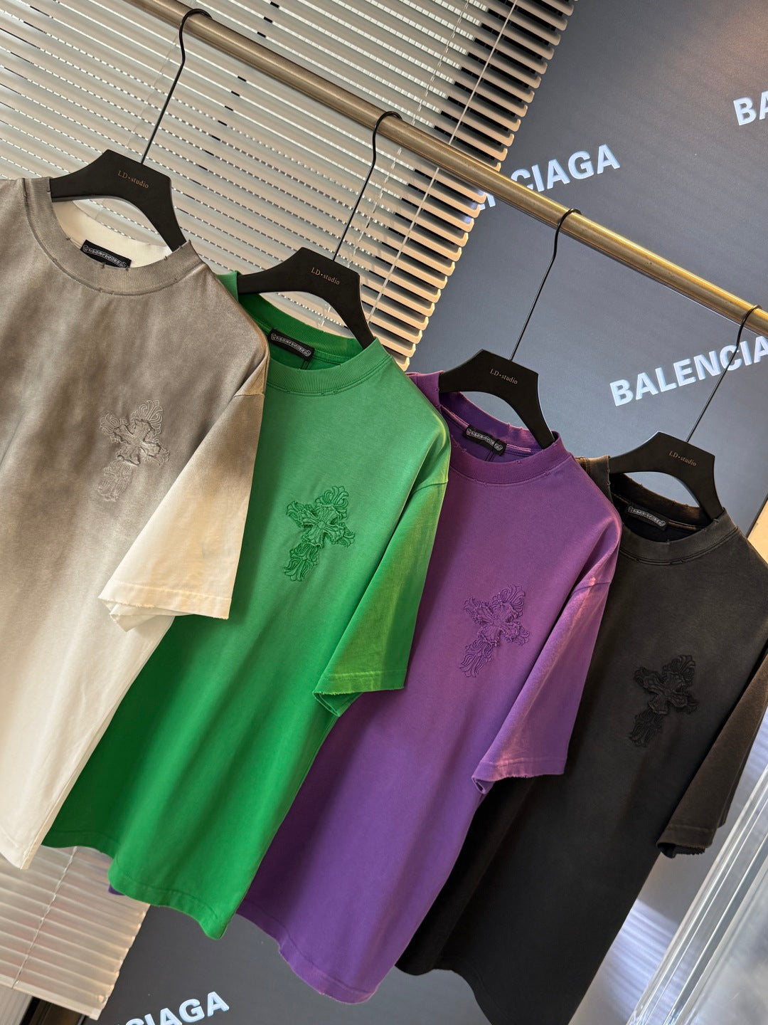 Short-sleeve T-shirts in off-white, green, purple, and black on hangers, chest graphic