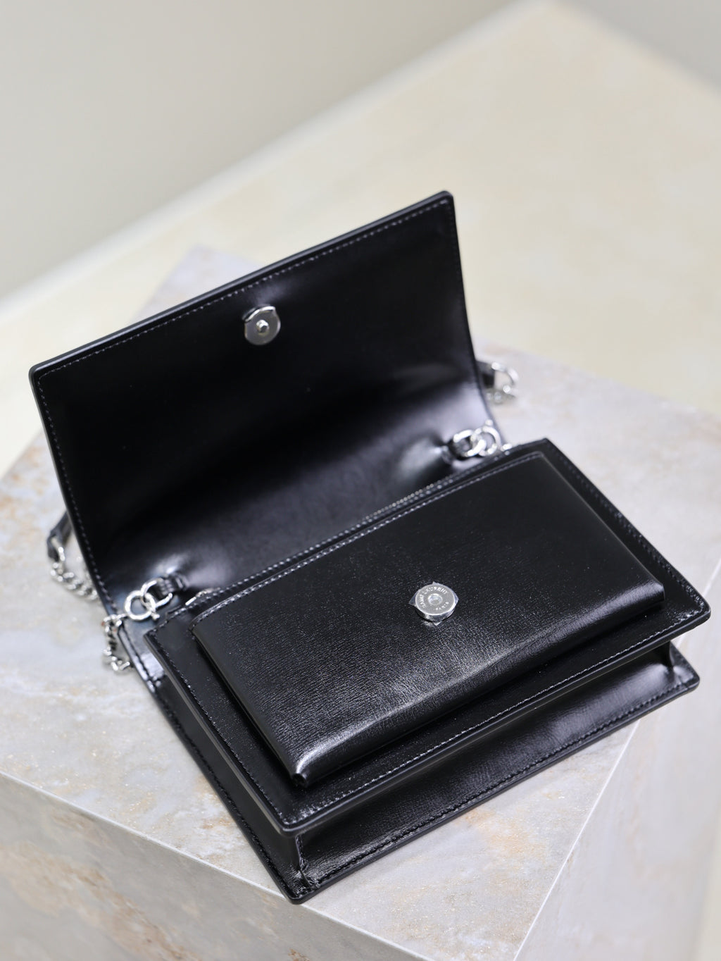 YSL black leather bag open with dual compartments, snap buttons and chain hardware