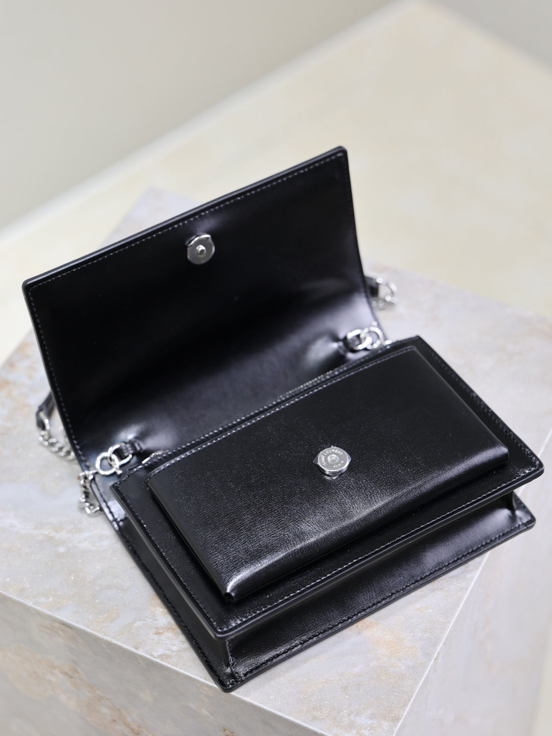 YSL black leather bag open with dual compartments, snap buttons and chain hardware