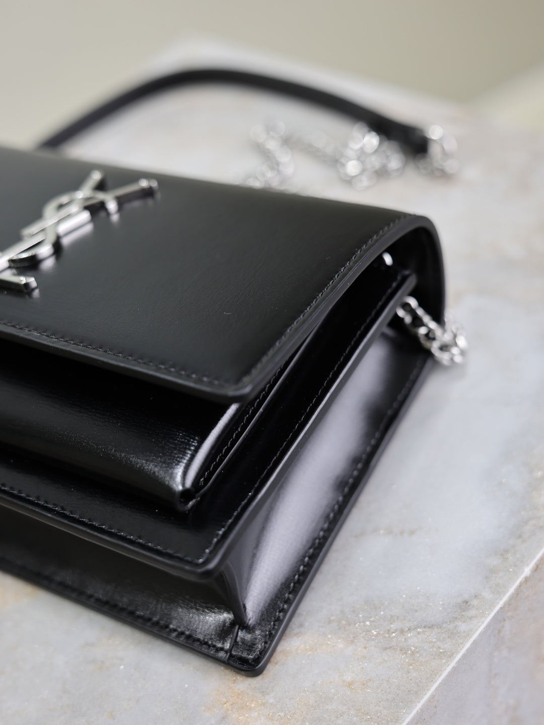 YSL black leather clutch bag with front flap and silver YSL logo, chain strap