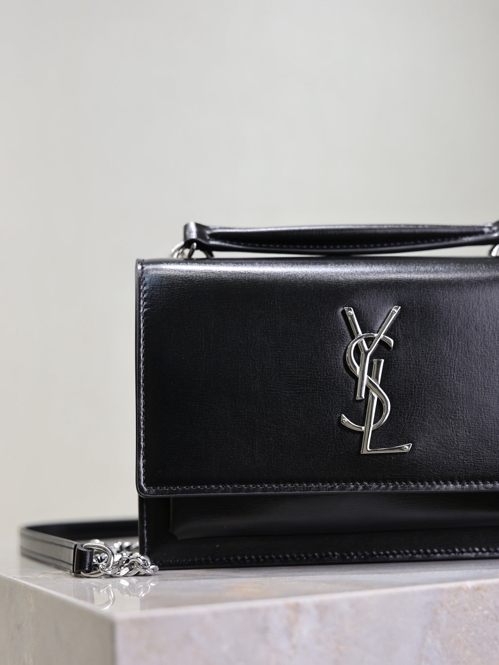 YSL black leather shoulder bag close-up with silver YSL logo on front flap