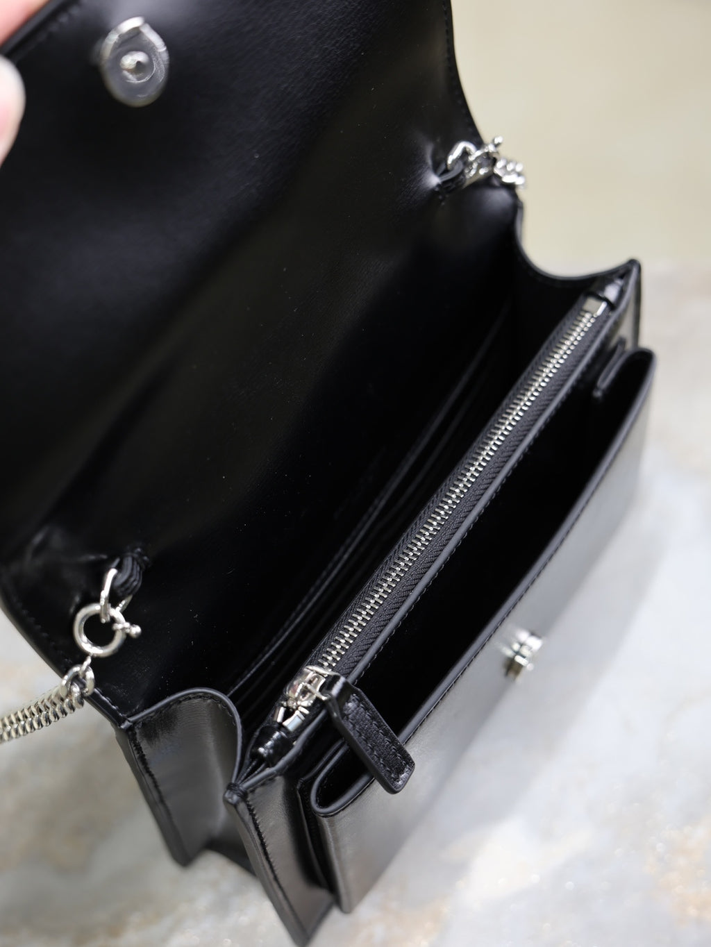 YSL black leather bag interior close-up with zipper, snap button and chain pull