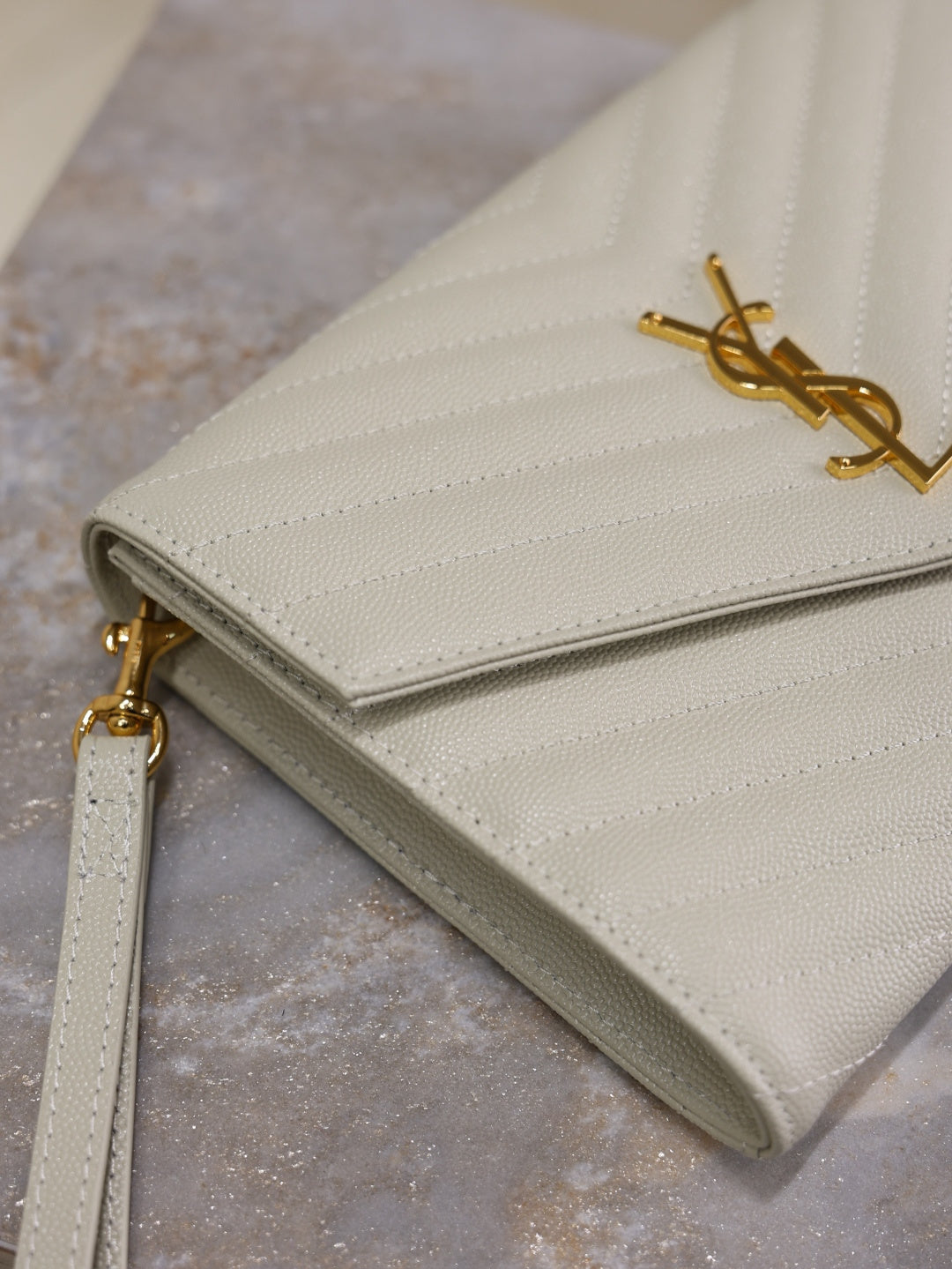 Women’s YSL small shoulder bag close-up, white quilted chevron with gold YSL logo