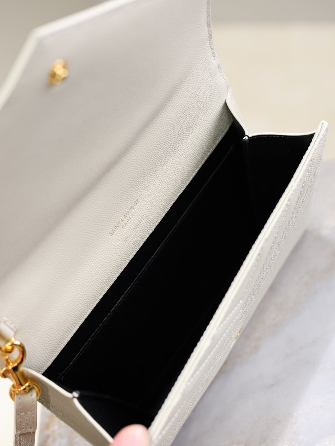 Women’s YSL small shoulder bag interior, black lining visible with gold hardware and strap