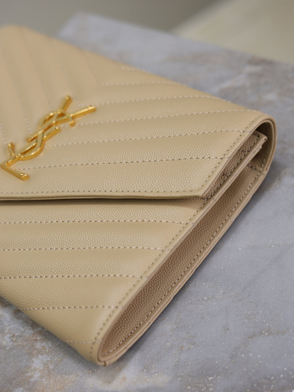 Quilted shoulder bag in light beige with gold YSL logo and flap closure