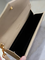 Beige small YSL bag interior with black lining and open flap; gold clasp detail