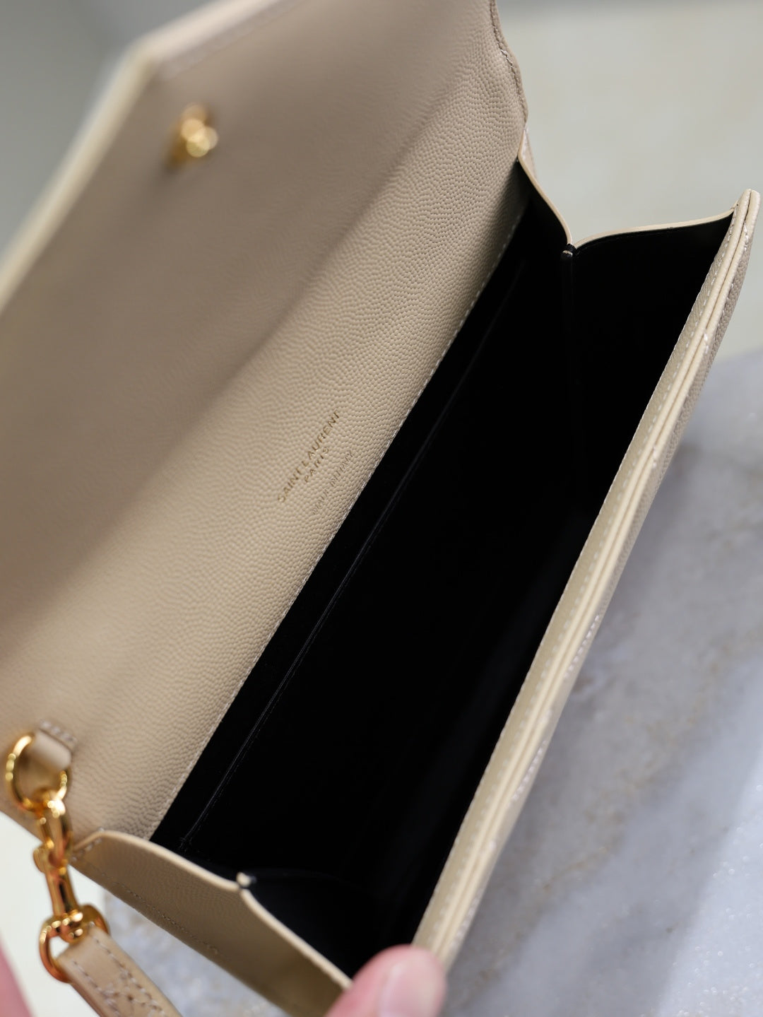 Quilted shoulder bag interior in light beige with black lining and gold clasp