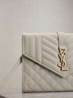 Small quilted YSL logo flap bag with side strap, light white leather.