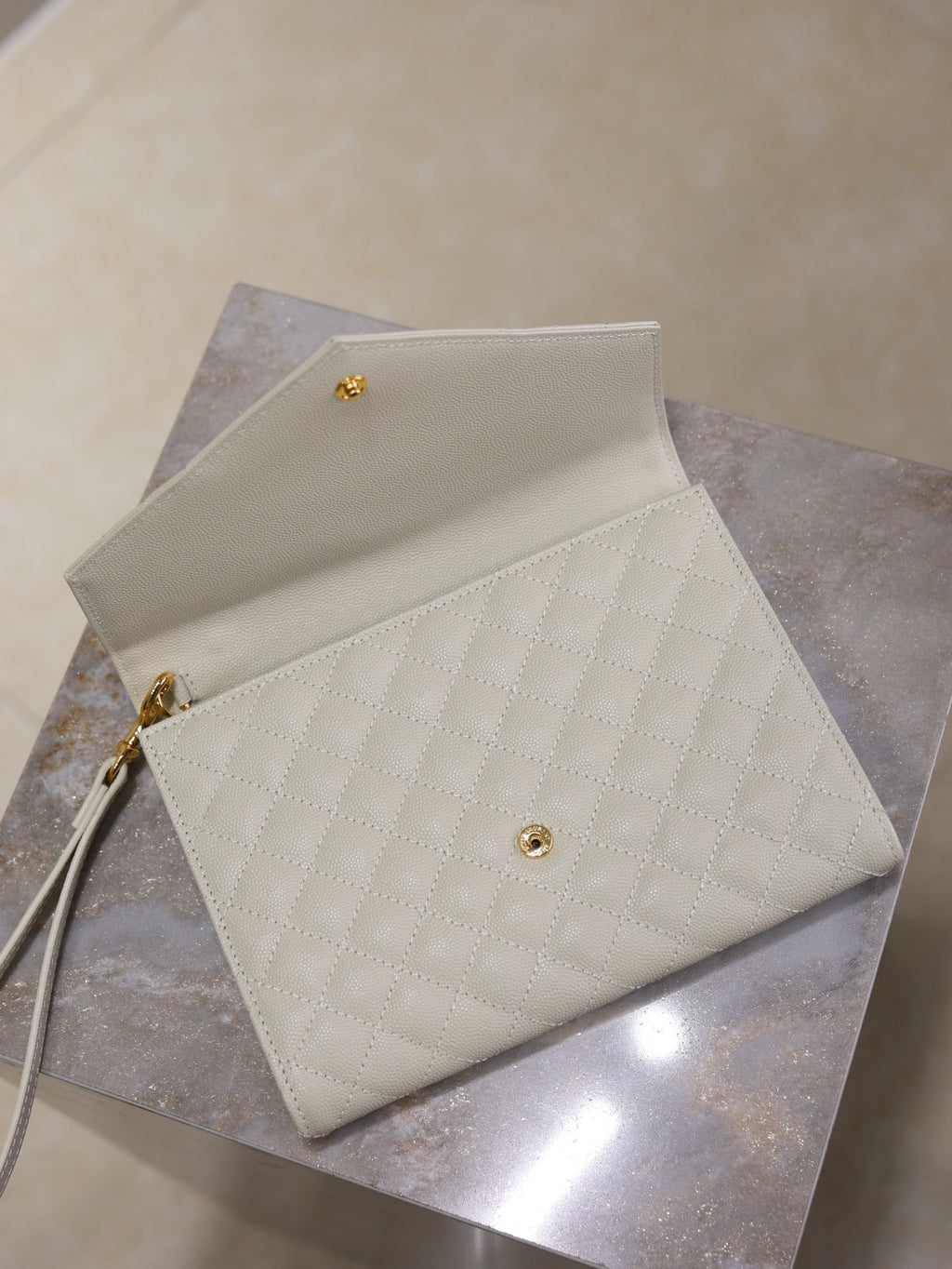 Light quilted shoulder bag with gold hardware, foldover flap, and short crossbody strap