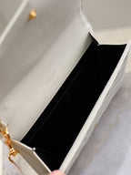 Small open quilted bag with YSL hardware, light white leather interior view.