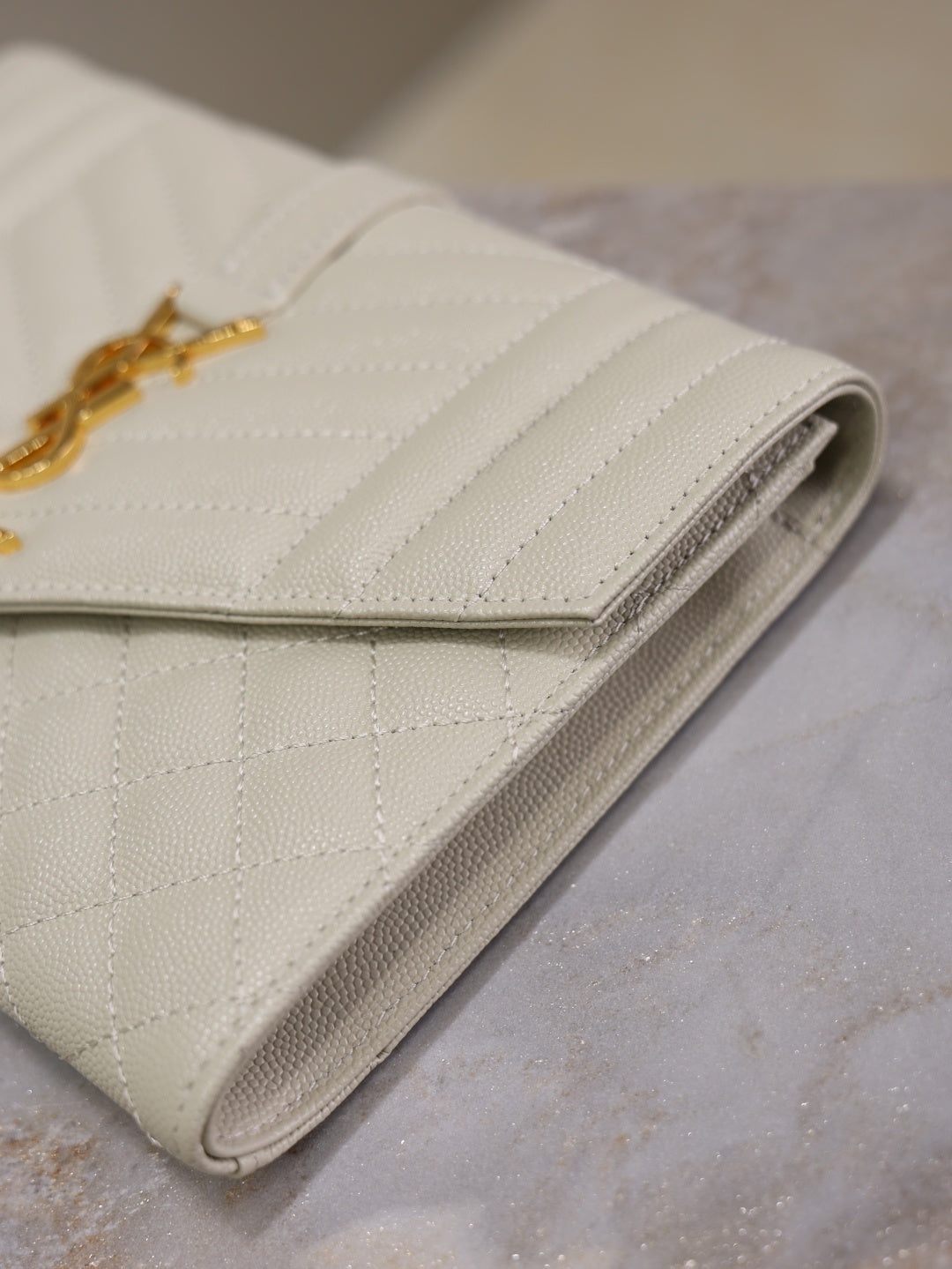 Small quilted fold-over clutch, light white leather with side seam detail.