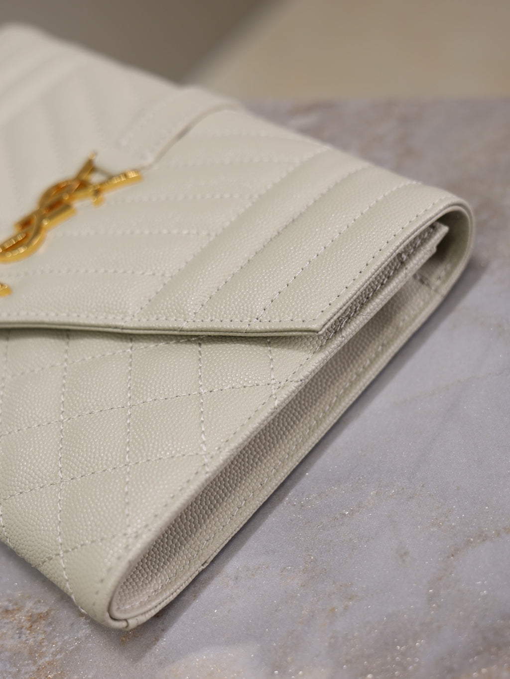 Quilted light leather-style foldover bag with gold YSL logo and gusseted edges