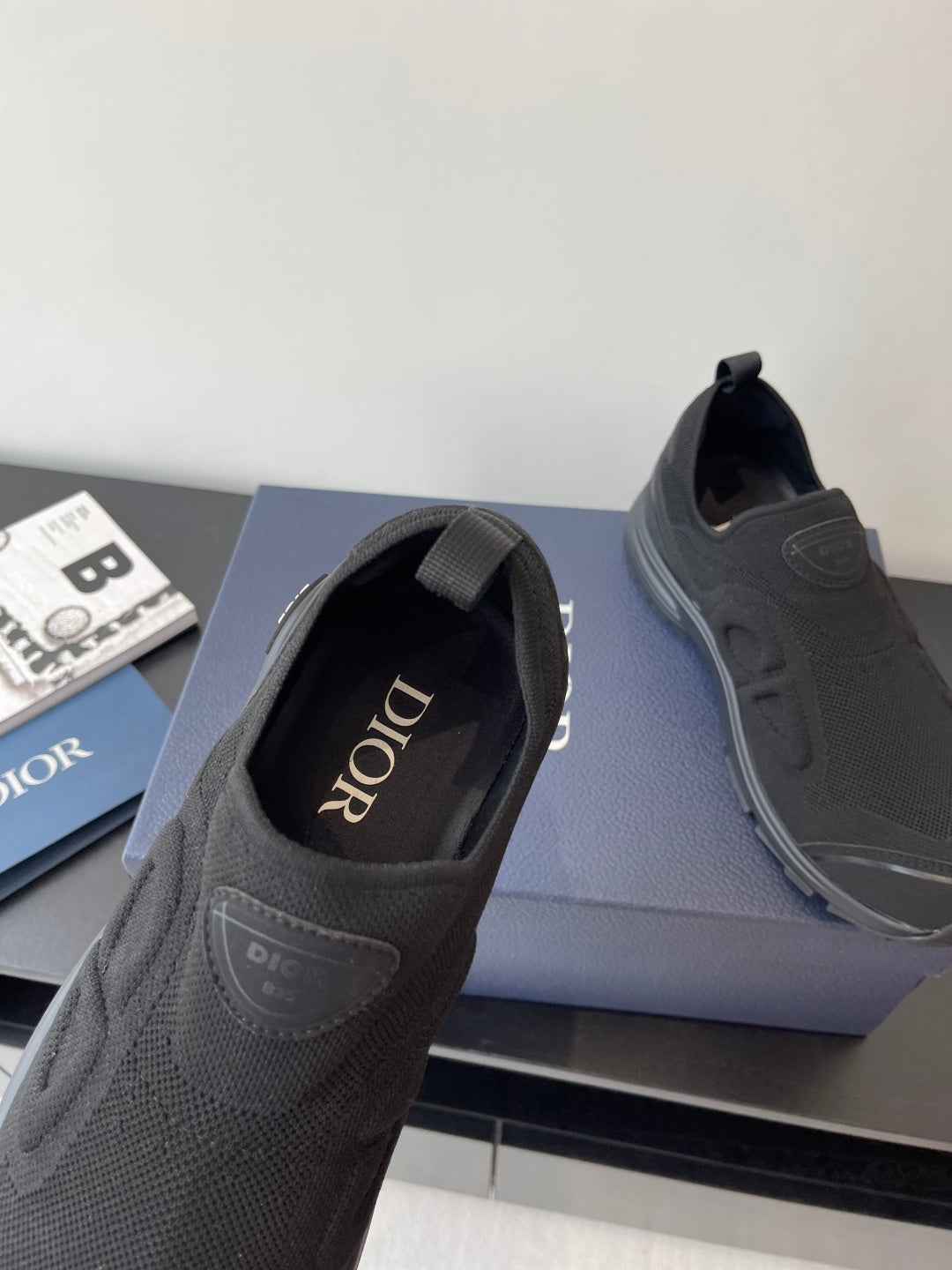 Dior slip-on sneaker close-up, dark gray textured upper, 'Dior' branding on side