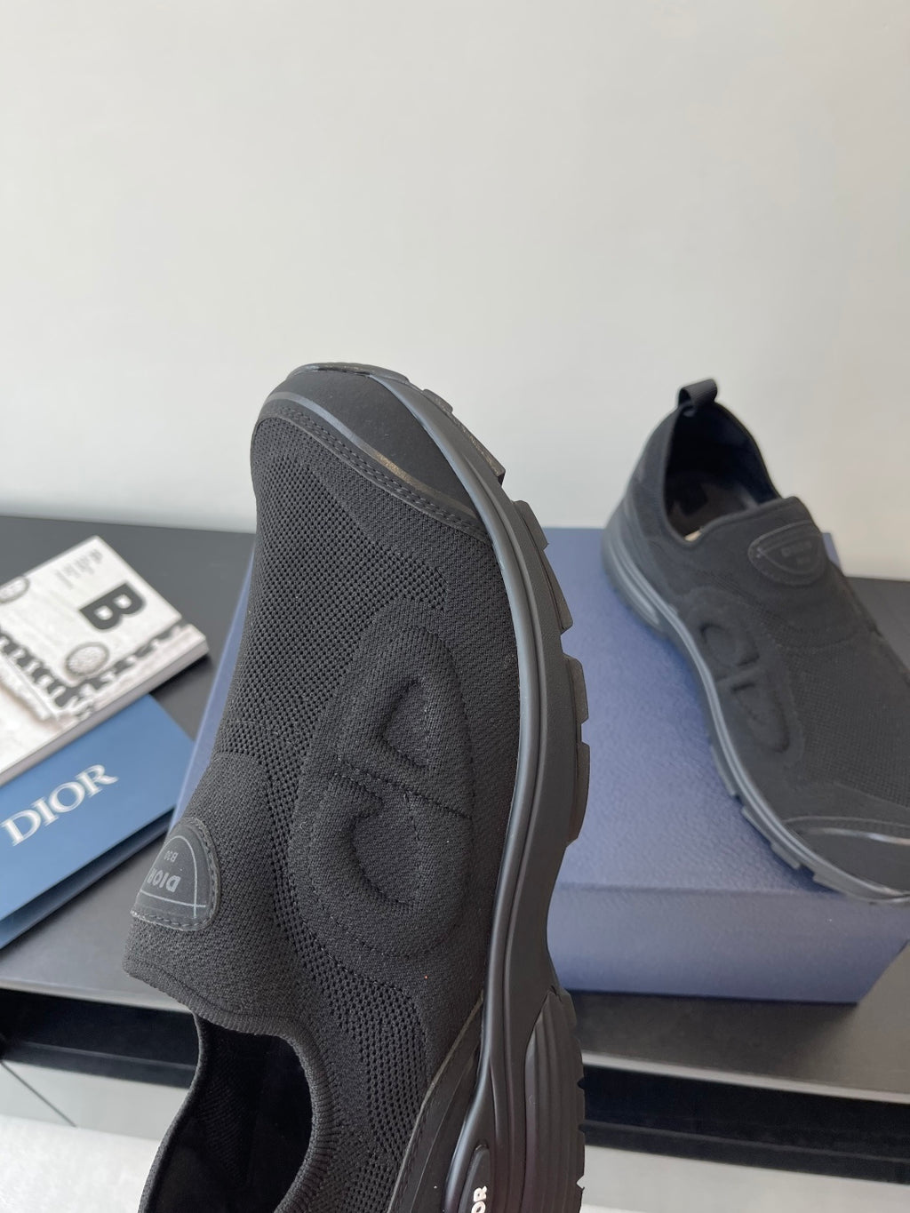 Dior slip-on sneaker side profile, dark gray textured upper, rubber sole edge