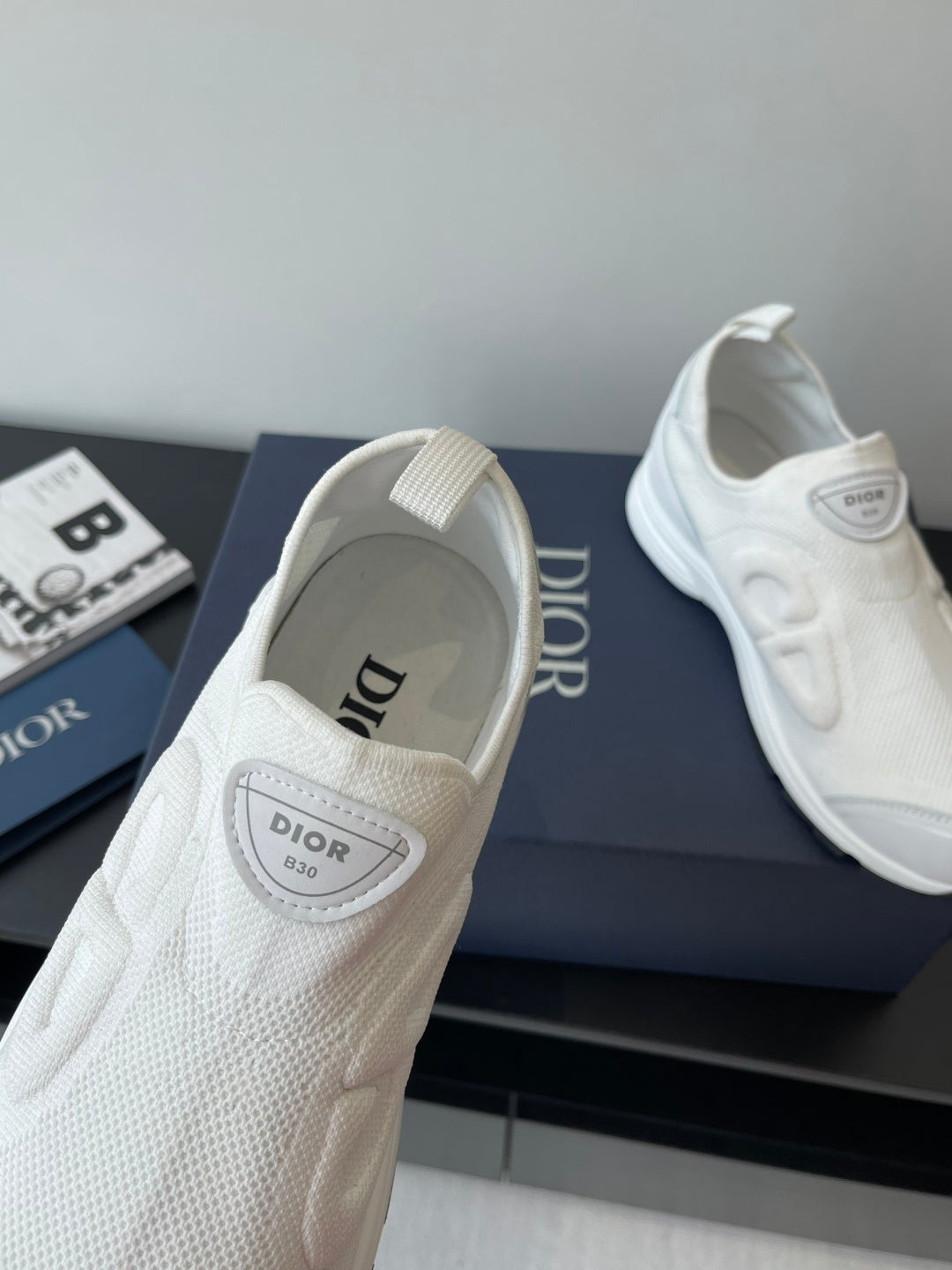 White Dior sneakers close-up, logo patch on tongue and side mesh texture