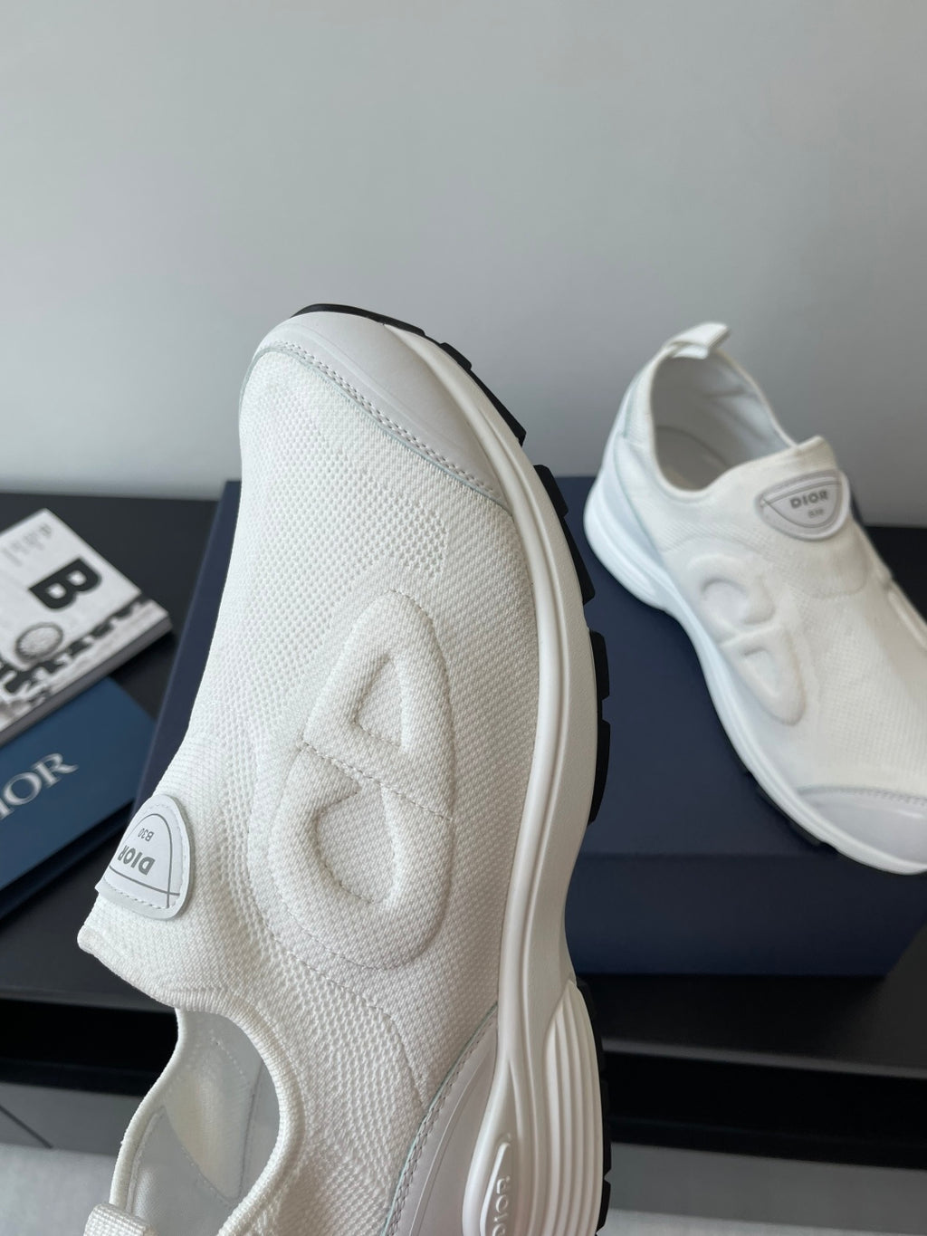 White Dior sneakers side view, textured upper with logo embossed on panels