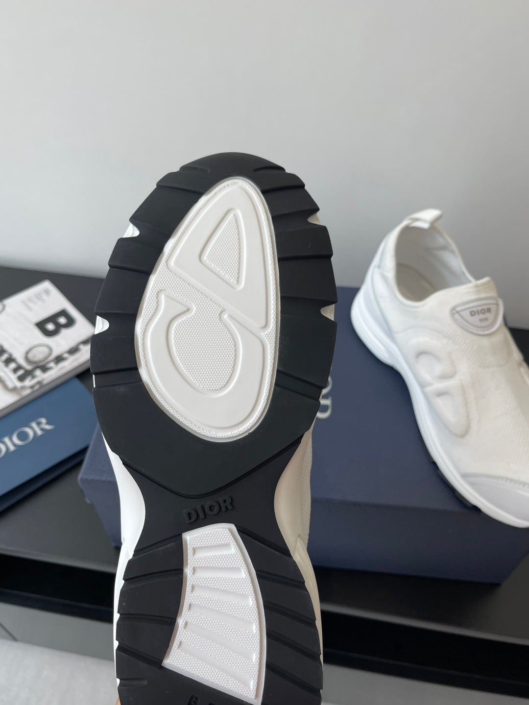White Dior sneakers with black outsole view, chunky tread and sculpted heel