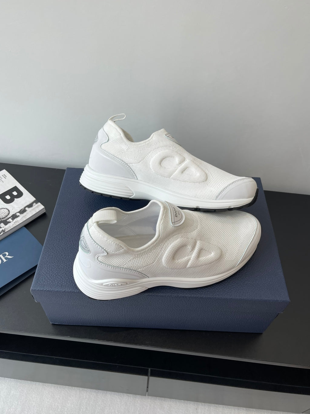 Pair of white Dior slip-on sneakers with wavy side logo and cushioned sole