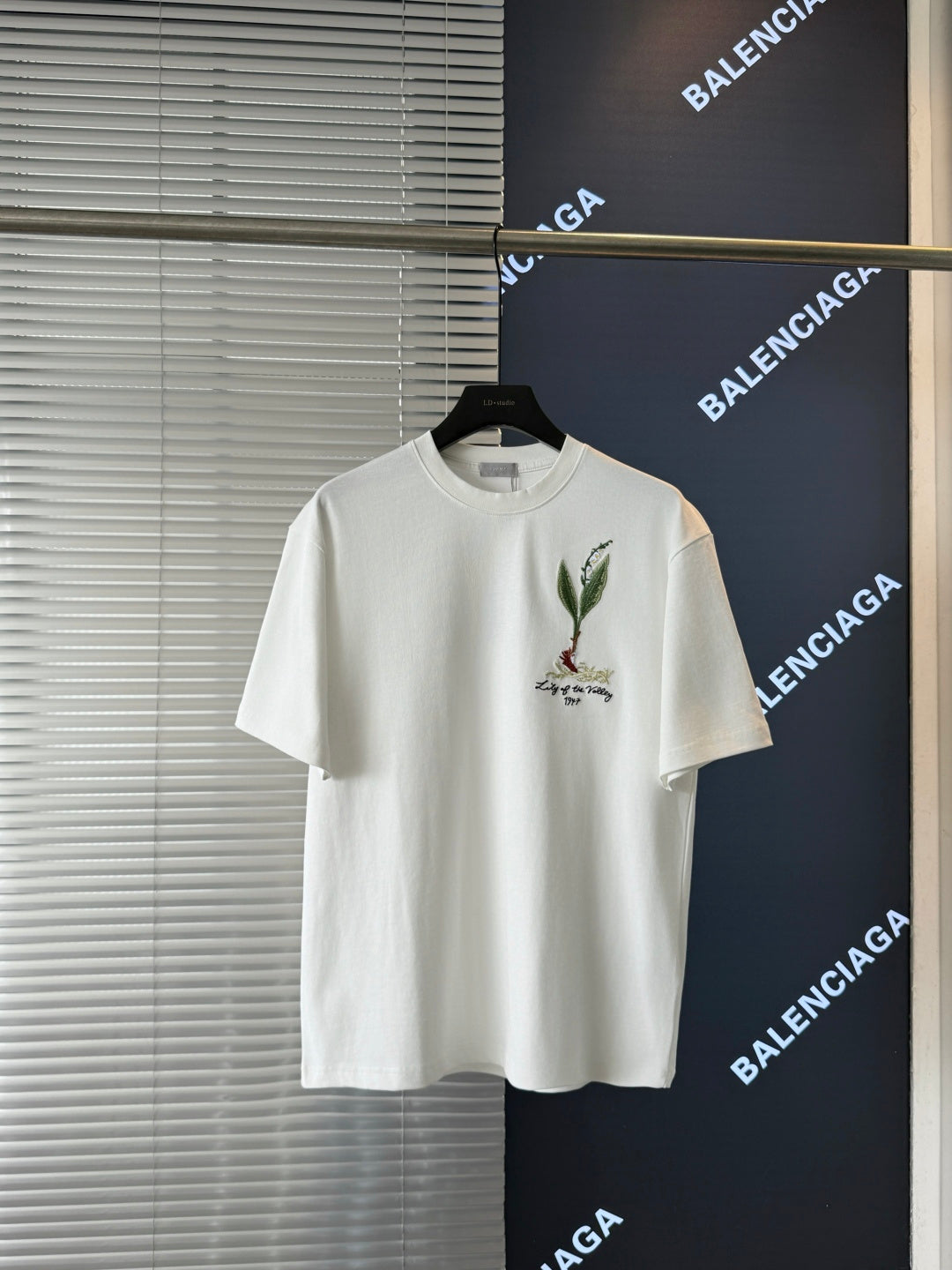 White short-sleeve T-shirt on hanger with chest botanical bird embroidery