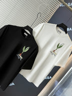 Black and white short-sleeve T-shirts laid on display, each with chest bird embroidery
