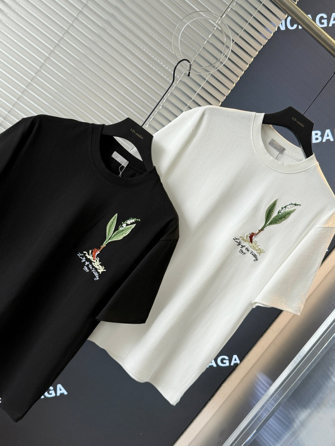 Black and white short-sleeve T-shirts laid on display, each with chest bird embroidery