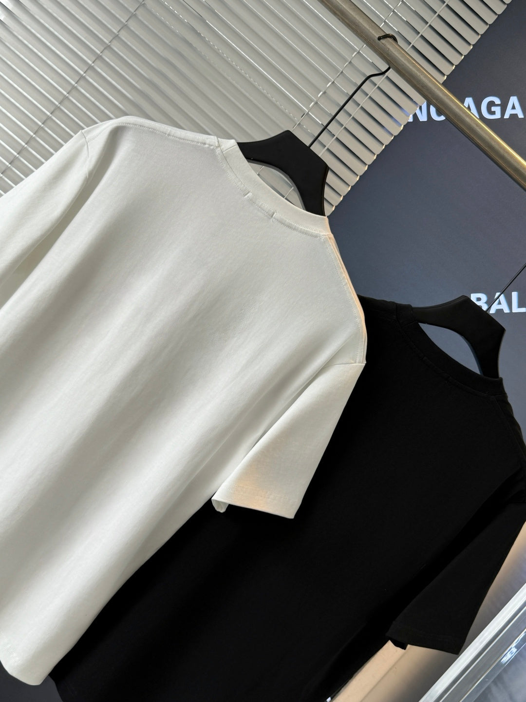 White and black short-sleeve T-shirts on hangers, crew necks, no visible embroidery