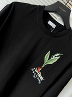 Black short-sleeve T-shirt close-up with green leaf and bird chest embroidery