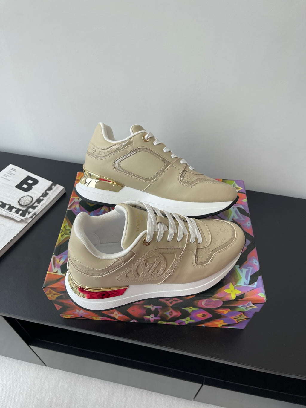 Louis Vuitton ladies low-top sneakers, light beige with white laces and red heel trim.