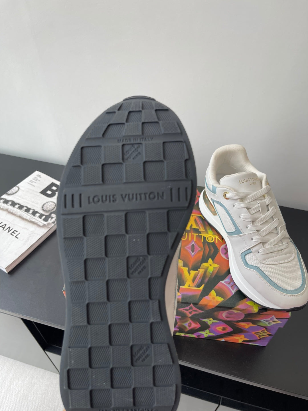 Shoe outsole view: dark tread sole with white and light blue upper