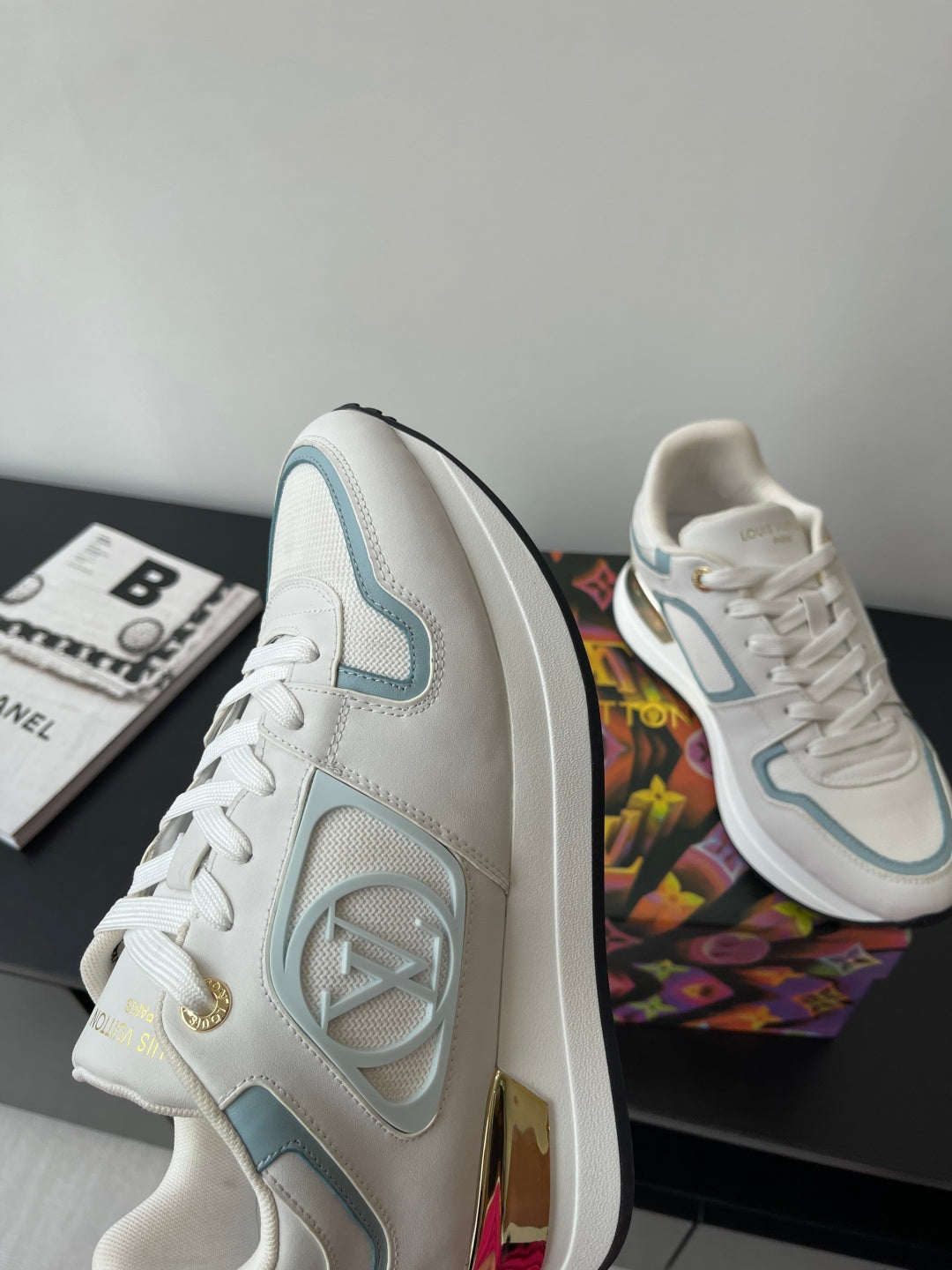 White and light blue high-profile sneakers with gold heel detail and lace-up front