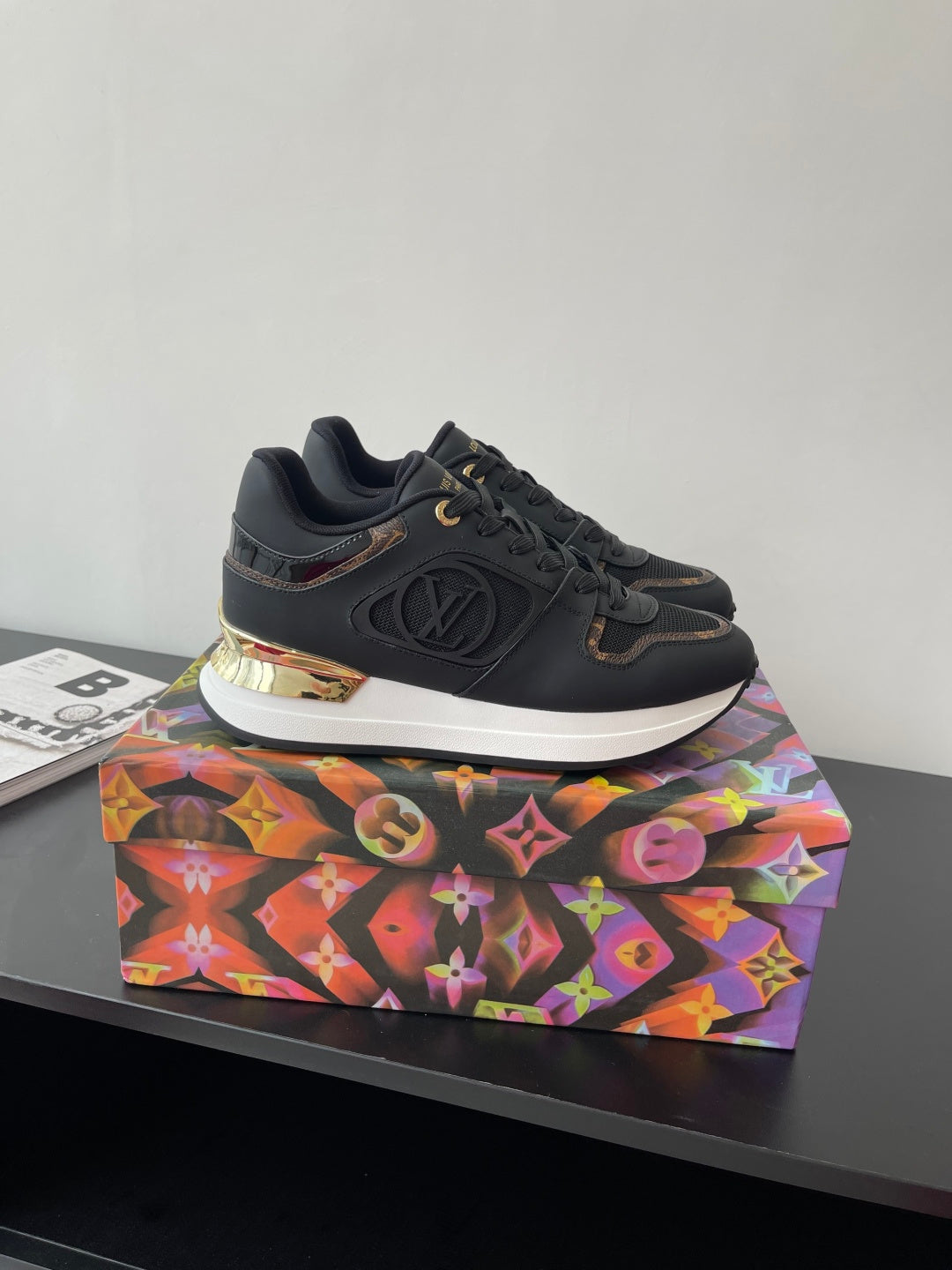 Ladies lace-up sneaker, dark upper with gold-trimmed sole and LV emblem detail.